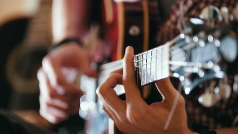 Male musician plays the guitar, hands close up, focus on the guitar fretboard
