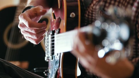 Male musician plays the guitar, hands close up