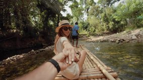 Female tourist floats on bamboo raft. Woman tourist enjoying the bamboo rafting on the river with man beautiful nature landscape on smartphone. Vacation, happy tourism, travel, follow me concept.
