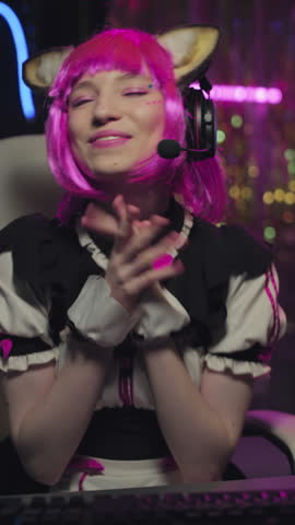 Vertical portrait of joyful gen Z girl cosplaying cute anime character wearing gaming headset live streaming