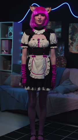 Vertical full length shot of modern young gen Z girl cosplaying neko maid anime character performing cute dance on camera