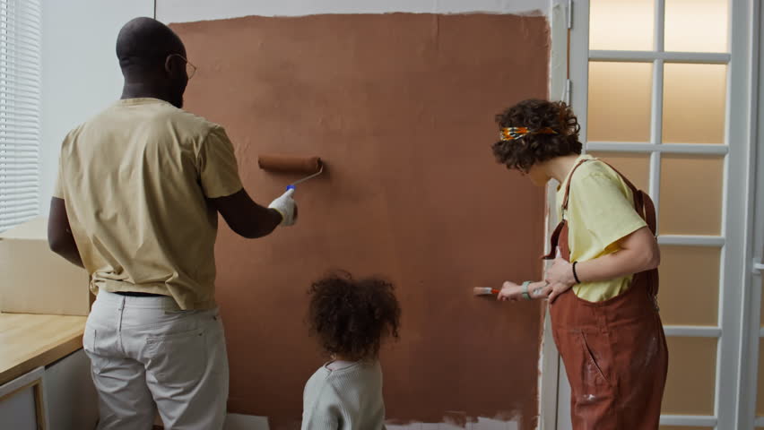 Back footage of multiracial family of father, mother and child painting wall while renovating nursery room in anticipation of future offspring Royalty-Free Stock Footage #3485025609