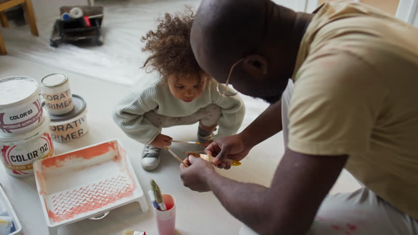 High angle footage of African American father explaining to little Biracial daughter what brush to use while renovating room, girl helping dad Royalty-Free Stock Footage #3485058337