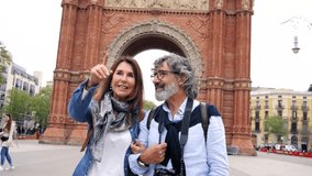 Mature love couple in their sixties walks hugging and chatting smiling on street of European city. Happy elderly couple pointing to a tourist spot to enjoy together on vacation or weekend getaway.  - Powered by Shutterstock - Get 15% off with code: PIKWIZARD15