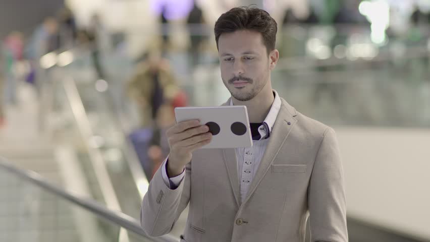Man Using Tablet against the Backdrop of a Bustling Street