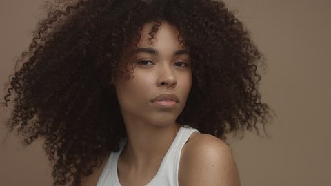 studio portrait of black model woman looking at camera, ideal skin concept huge afro curly hair
