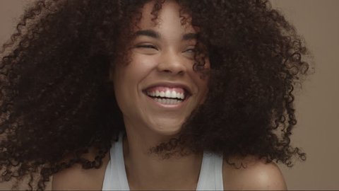 happy laughing black woman with wind moving her curly hair in sytdio