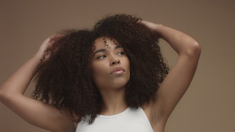 closeup portrait of mixed race black woman shaked head and her curly hair flying in air slowly. Touching it