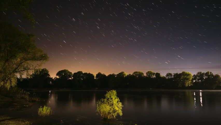 4k Timelapse Night Sky Above River. Star Lines Move In Sky. Star Trails On Night Sky Background. Amazing Starry Effects. From Dusk To Dawn. Night Sky Turns Into Morning. Dawn Is Coming. Time Lapse