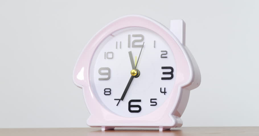 4K footage Close-up Front view Time-lapse, White house shaped alarm clock is placed on a table with a white background, Say time 11.35 a.m.