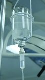 Close-up of vitamin IV drip chamber dripping on medical clinic. Dripping for intravenous infusion during surgery. Vertical video