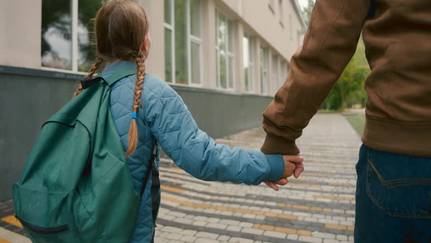 Back view little girl walking street city outdoors holding hands with dad primary school lessons smiling safety joy happiness family stroll trust togetherness protection child parenthood positive bond Royalty-Free Stock Footage #3485581355