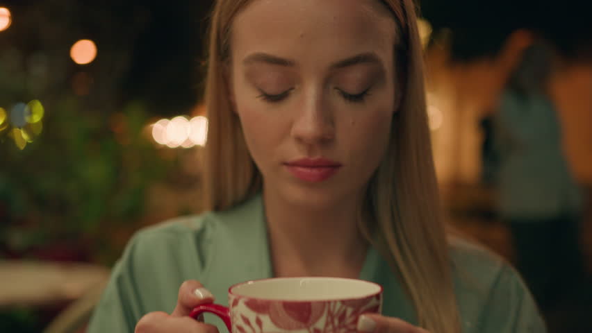Close up woman drinking hot warm tea coffee holding cup cafe street outside evening enjoying relax nightlife smiling looking at camera female girl beverage cozy satisfaction face city weekend resting