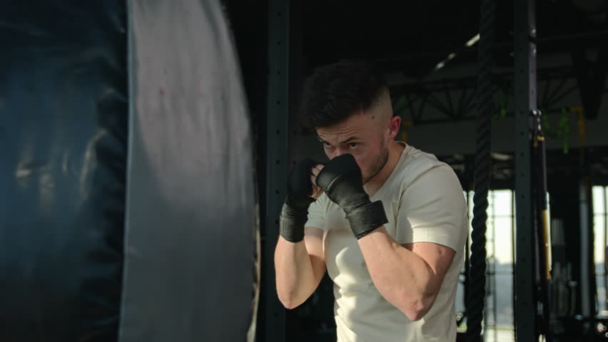 Strong man in boxing gloves training with punching bag in gym professional box workout exercise sports athlete boxer fighter champion with power strong motivation hitting beating prepare for fighting