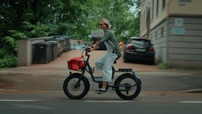 Handheld real life looped shot of woman ride cute electric city bike downhill on fast speed on busy street. cars pass by she rides on bike lane. Commuting and cycling in everyday life - Powered by Shutterstock - Get 15% off with code: PIKWIZARD15