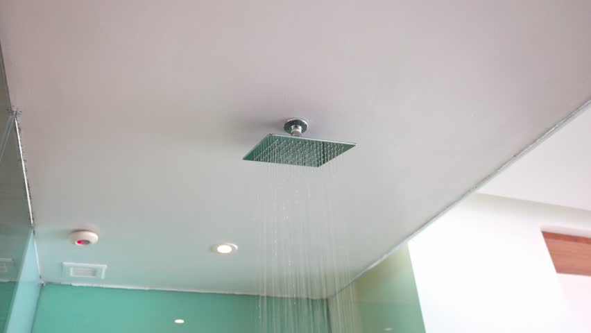 View of a luxurious hotel shower room featuring a large ceiling-mounted rainfall shower head, additional wall-mounted shower head, recessed spotlights and transparent glass enclosure. Royalty-Free Stock Footage #3485721953