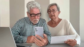Video call concept. Elderly couple sitting at home talking remotely with doctor on mobile phone webcam to communicate the results of some medical tests,  waits for doctor's consultation
