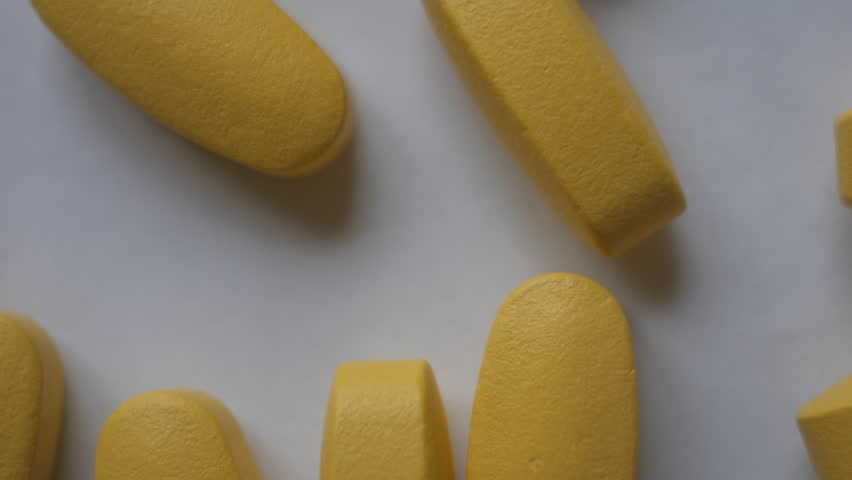 yellow pills scattered on white surface: стоковое видео (без лицензионных п...
