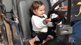 innocent toddler cute expression while playing with car handle at day from flat angle video is taken at rajasthan, India.