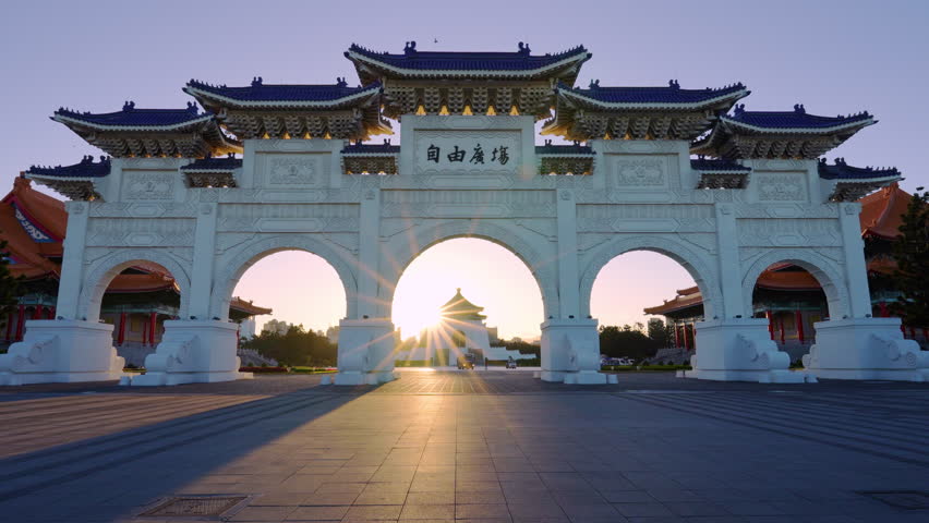 Chiang Kai-shek Memorial Gate with morning sunlight and men cycling in Taipei, Taiwan. The meaning of the Chinese text on the arch is "Liberty Square"