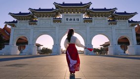 Slow motion video, Chiang Kai  Shek Memorial Arch with morning sunlight and Asian women in Taipei, Taiwan. The meaning of the Chinese text on the archway is 