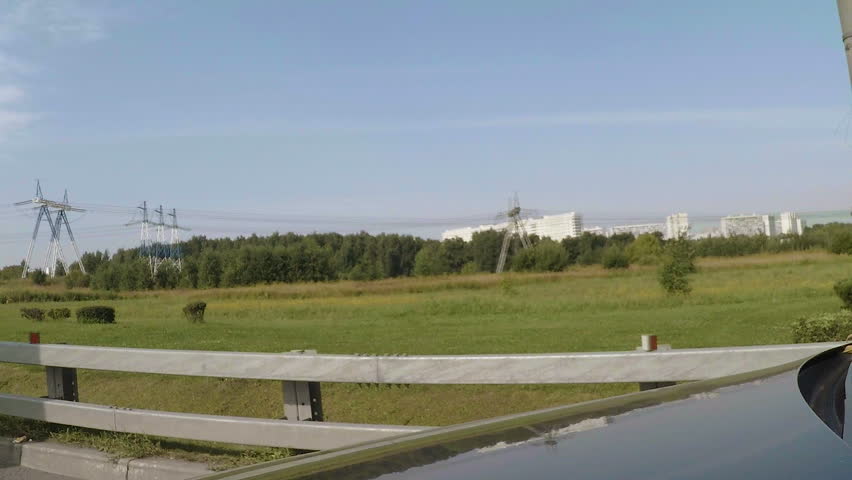 The car rides on the road. A residential apartment building in the background