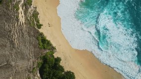 The pristine sandy beach of Kelingking on the island of Nusa Penida, Bali. Drone video of turquoise ocean water near green limestone rocks. A famous natural monument.