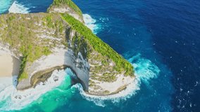 Pristine sandy Kelingking Beach on Nusa Penida island Bali. Aerial drone video of turquoise ocean water by green limestone cliffs. Famous natural landmark
