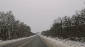 Winter road snowfall. An empty rural road without cars, covered with snowdrifts. Travel in bad weather. Winter cloudy landscape with a country road. Tracks of passing cars. Horizontal 4k nature video