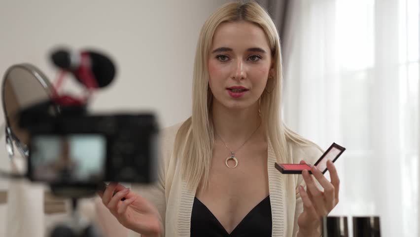 Young woman making beauty and cosmetic tutorial video content for social media. Beauty blogger smiles to camera while showing how to beauty care to audience or followers. Blithe Royalty-Free Stock Footage #3486023333