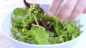 Close-up of the cook's hands as he mixes the salad in a bowl. Slow motion video.