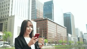 A female businessperson walking around the city with a smartphone