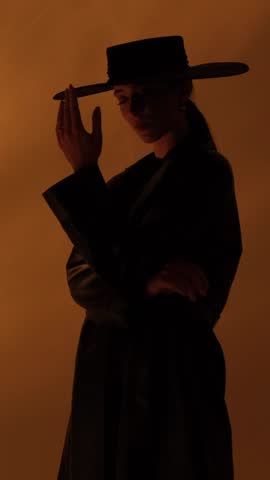 Fashion portrait of a girl in the studio with a black hat with golden decorations. Jewelry. Vertical video.