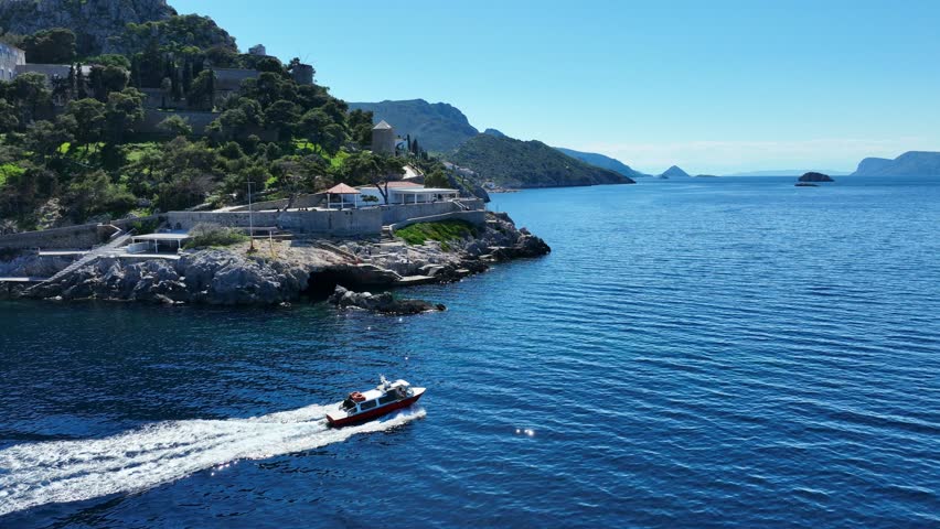 Aerial drone cinematic video of water taxi cruising near picturesque and historic main village of Hydra or Ydra island well know for captain