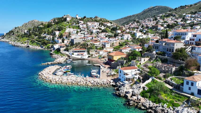 Aerial drone cinematic video of small picturesque seaside village and harbour of Kaminia located near main village of Hydra island accessible by footpath, Saronic gulf, Greece