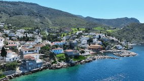 Aerial drone cinematic video of small picturesque seaside village and harbour of Kaminia located near main village of Hydra island accessible by footpath, Saronic gulf, Greece