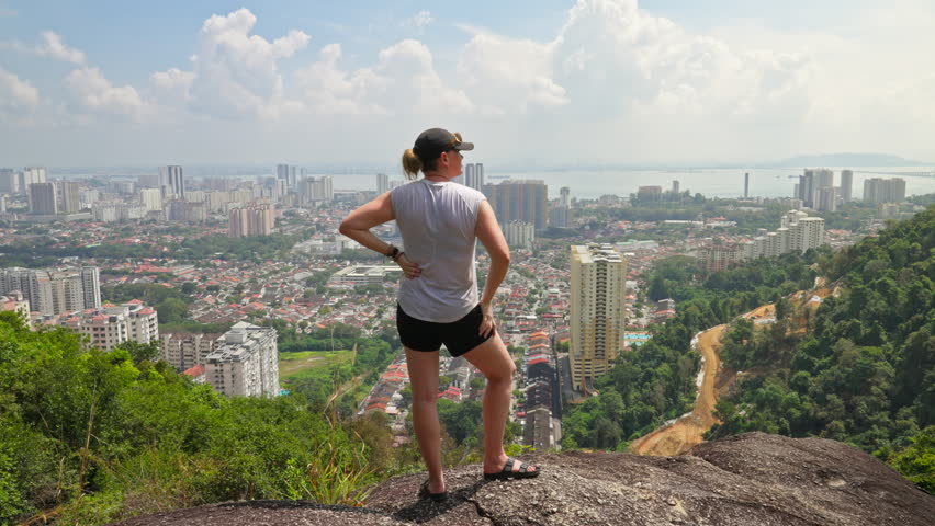Woman standing on top of a hill overlooking the cityscape view of George Town on the island of Penang, Malaysia