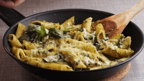 Traditional Italian pesto pasta, chef cooking penne with green basil sauce in pan, close up of Italian cuisine, vegan food. - Powered by Shutterstock - Get 15% off with code: PIKWIZARD15