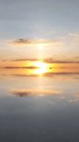 Salar de Uyuni in Bolivia during sunset. Aerial image taken with a drone. Uyuni Salt Flats. Altiplano, Bolivia. Rainy Season. Tunupa Volcano. Clouds Reflection on Water in Lake Surface. Vertical video