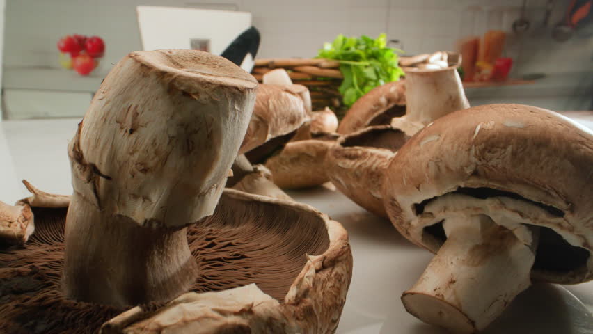 champignon mushrooms on the kitchen table against the background of a wicker basket. High quality 4k footage
