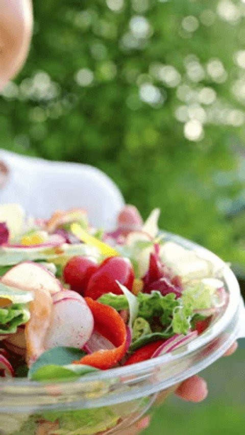 Sporty Woman Eating Vegetarian Salad. Fresh colored salad with lettuce leaves and tomato into bowl, served with healthy food ingredient. Family dinner with organic salad, top view. Summer food outdoor Video Stok