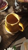 Vertical video. Woman pouring tea from teapot during morning breakfast in kitchen.