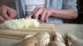 onion slicing, guy cutting onions on wooden board, mushrooms in the foreground, offset focus, slow motion