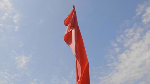Red flag waving against clean blue sky