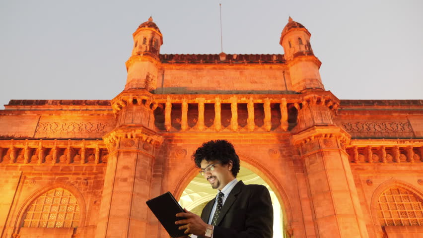 4k footage of office going young man using mobile phone, tablet in front of Gateway of India.