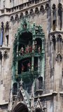 Panoramic view of theatrical puppet show on tower in Marienplatz town hall of Marien Square in Munich, Bavaria, Germany. Vertical video. Taken from hand. High quality 4k footage