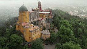 Pena Palace in Sintra, Portugal. Fairytale castle on a hill in the clouds, aerial video in 4K, 60fps slow motion.