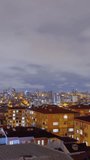 Timelapse, vertical video: fast moving clouds in the dark sky over typical turkish residential buildings with warm illumination, blinking windows in Istanbul, Turkey at night: time lapse concept