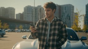 Caucasian man user driver using smartphone mobile phone messaging online in city outdoors happy joyful male guy millennial businessman cheerful smiling stand near luxury automobile travel by auto car - Powered by Shutterstock - Get 15% off with code: PIKWIZARD15