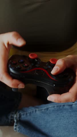 Mom and son of European appearance smile playing video games using joysticks sitting on the couch in a stylish home interior